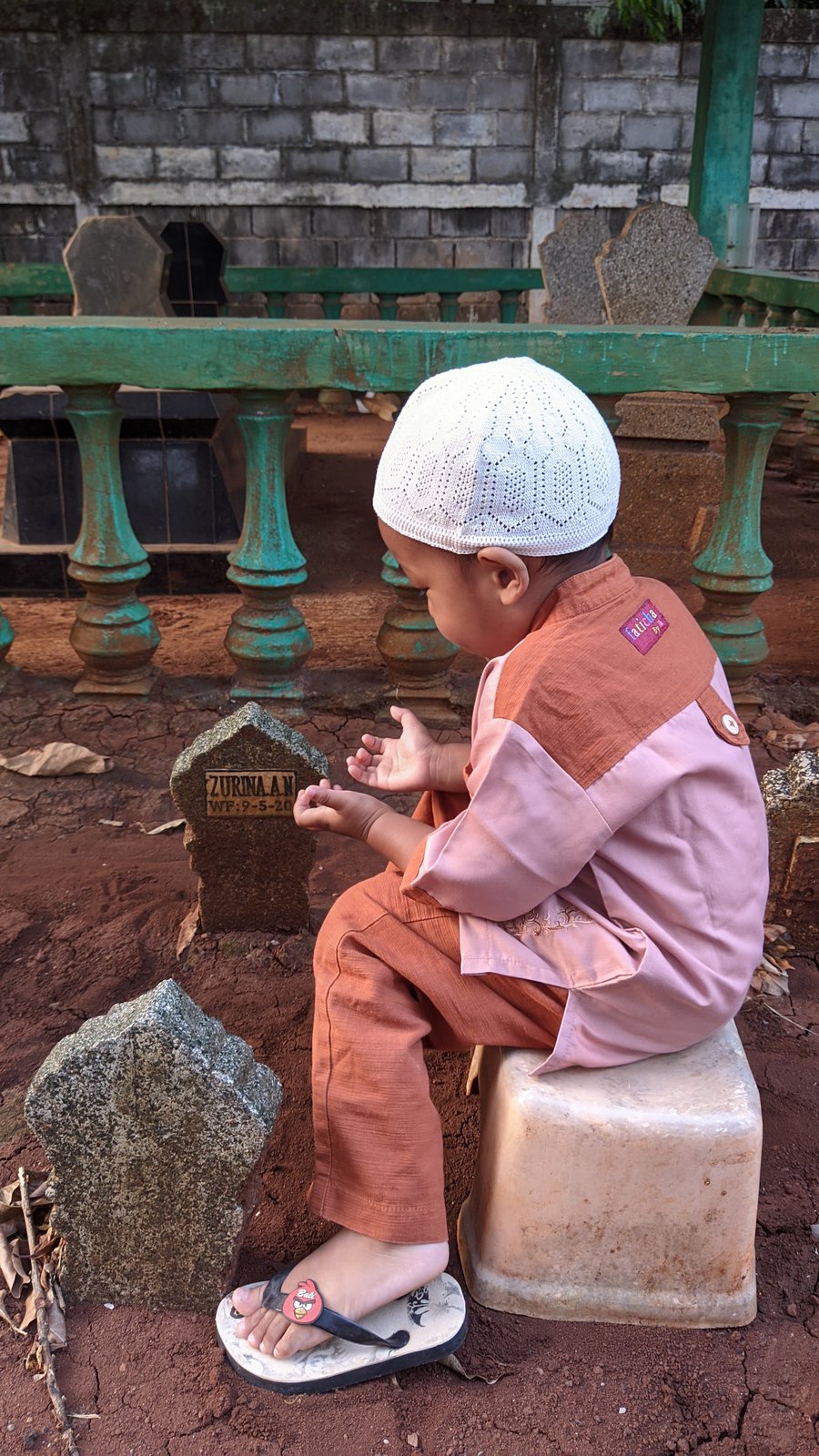 Seorang anak berdoa di samping makam putri pertama keluarga